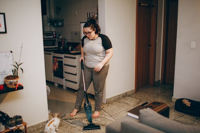 A woman cleaning the floor  with a vacuum 